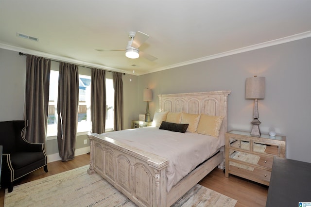 bedroom with ceiling fan, light wood finished floors, visible vents, and crown molding