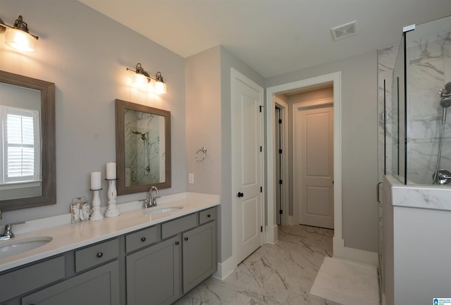 bathroom with double vanity, marble finish floor, a marble finish shower, and a sink