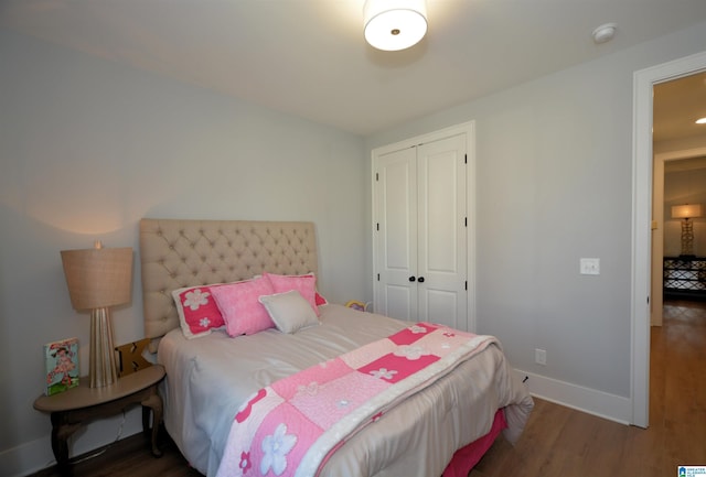 bedroom with baseboards, dark wood finished floors, and a closet