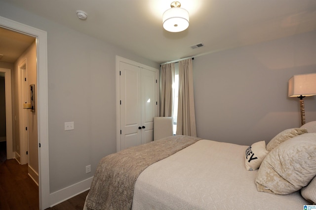 bedroom with dark wood-style floors, a closet, visible vents, and baseboards