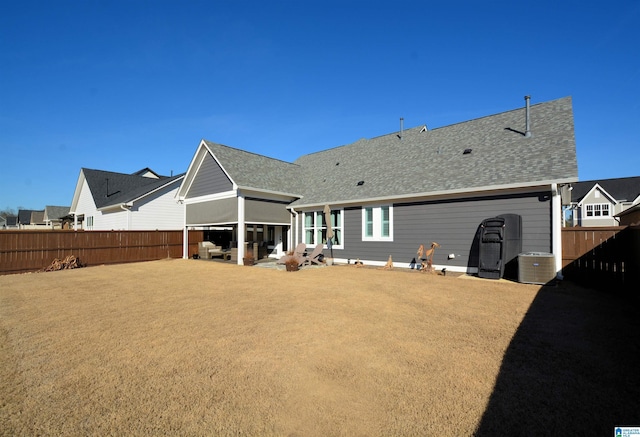 rear view of house featuring fence private yard, a shingled roof, a yard, and a patio