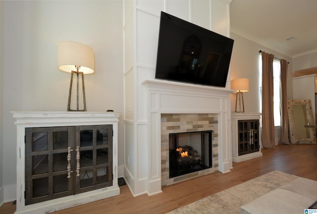 living room with ornamental molding, a fireplace, and wood finished floors