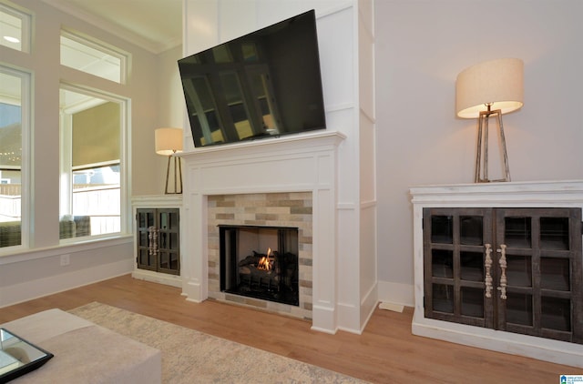 unfurnished living room with ornamental molding, a fireplace, baseboards, and wood finished floors