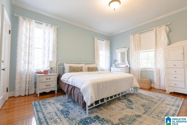 bedroom with hardwood / wood-style flooring, crown molding, and multiple windows