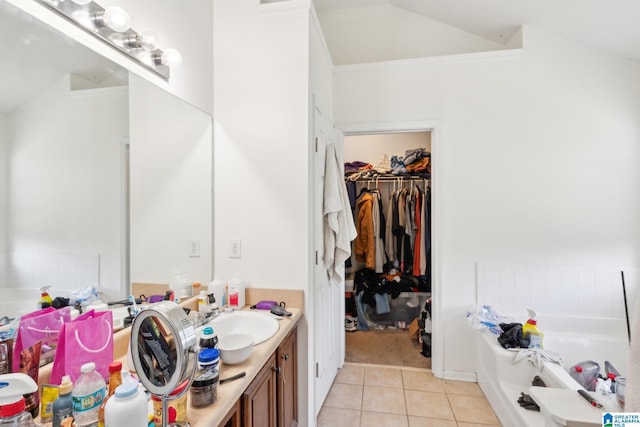 bathroom with tile patterned floors, a tub to relax in, lofted ceiling, and vanity