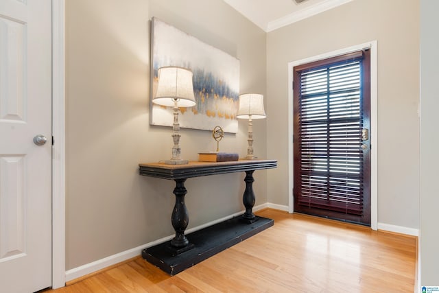 foyer entrance with crown molding and hardwood / wood-style floors