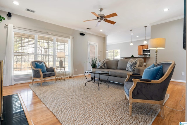 living room featuring a healthy amount of sunlight, crown molding, light hardwood / wood-style floors, and ceiling fan