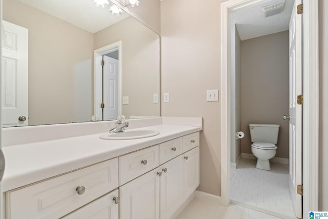 bathroom with a textured ceiling, toilet, vanity, and tile patterned flooring