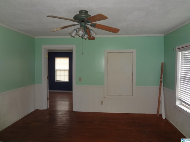 empty room with crown molding, dark wood-type flooring, and ceiling fan