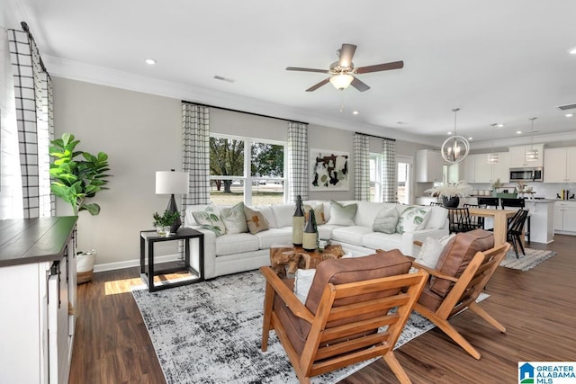 living room with ceiling fan with notable chandelier, dark hardwood / wood-style flooring, and ornamental molding