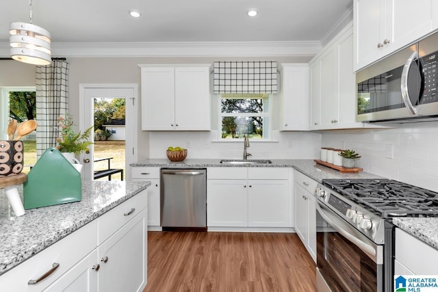 kitchen featuring white cabinets, crown molding, appliances with stainless steel finishes, and sink