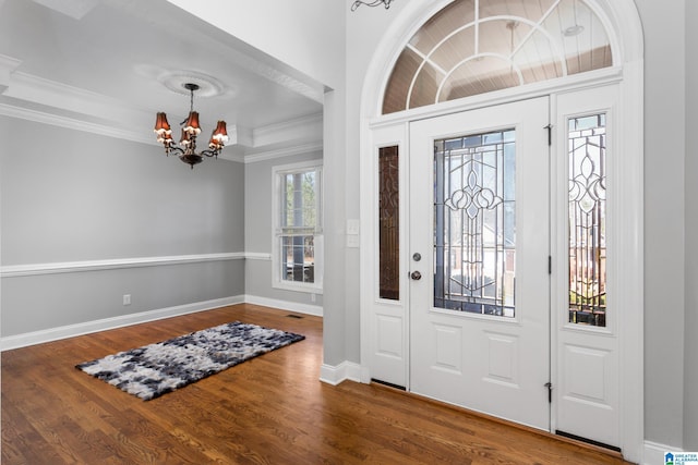 entrance foyer featuring a raised ceiling, an inviting chandelier, crown molding, and hardwood / wood-style flooring