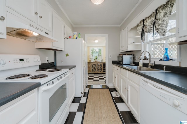 kitchen with dark floors, dark countertops, white cabinetry, a sink, and white appliances