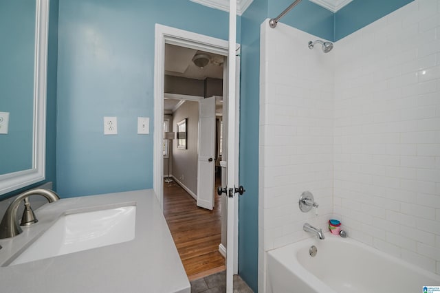 bathroom with washtub / shower combination, a sink, and wood finished floors