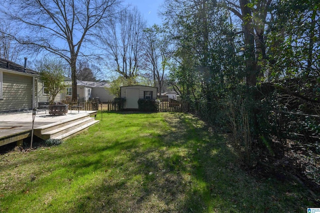 view of yard with an outbuilding, a fenced backyard, a fire pit, a wooden deck, and a storage unit