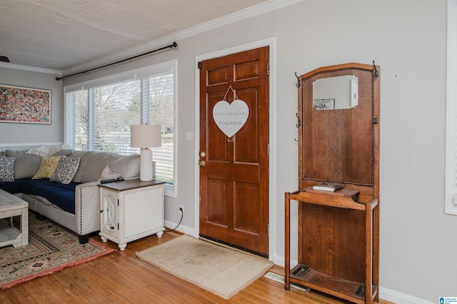 foyer entrance with baseboards, ornamental molding, and wood finished floors