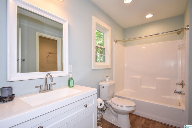 bathroom with wood finished floors, toilet, vanity, shower / bathtub combination, and recessed lighting