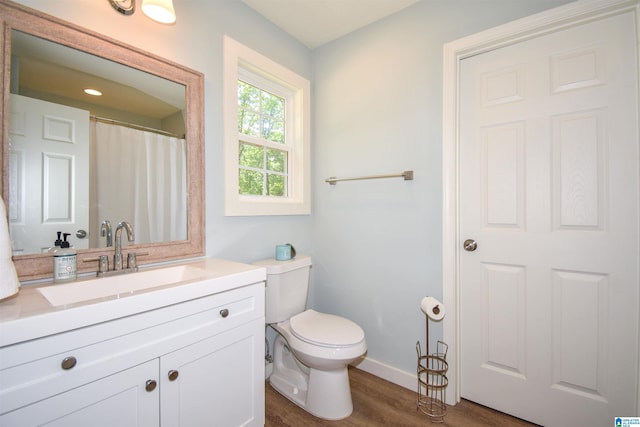 bathroom with wood finished floors, toilet, vanity, and baseboards
