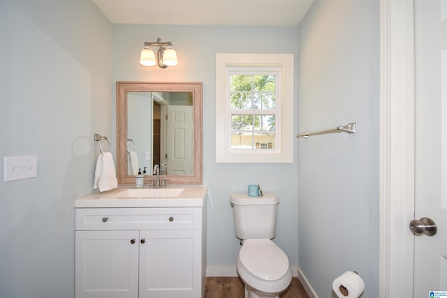 bathroom with vanity, toilet, baseboards, and wood finished floors