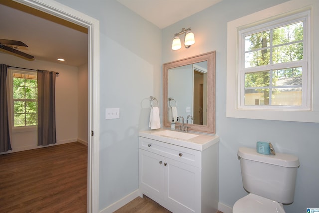 bathroom featuring wood finished floors, baseboards, toilet, a ceiling fan, and vanity