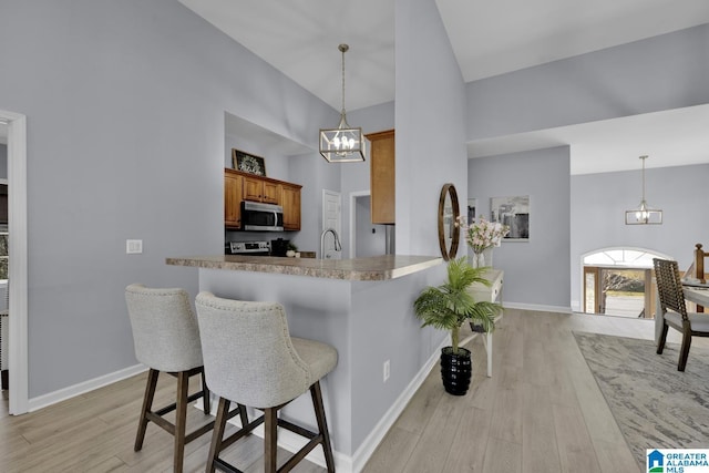 kitchen with light countertops, stainless steel microwave, a notable chandelier, and a kitchen bar