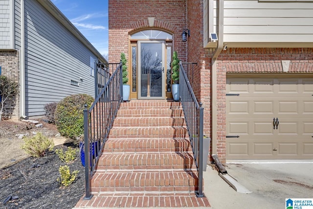 entrance to property with a garage and brick siding