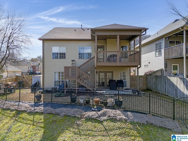 rear view of house featuring a patio, a balcony, a fenced backyard, roof with shingles, and stairs