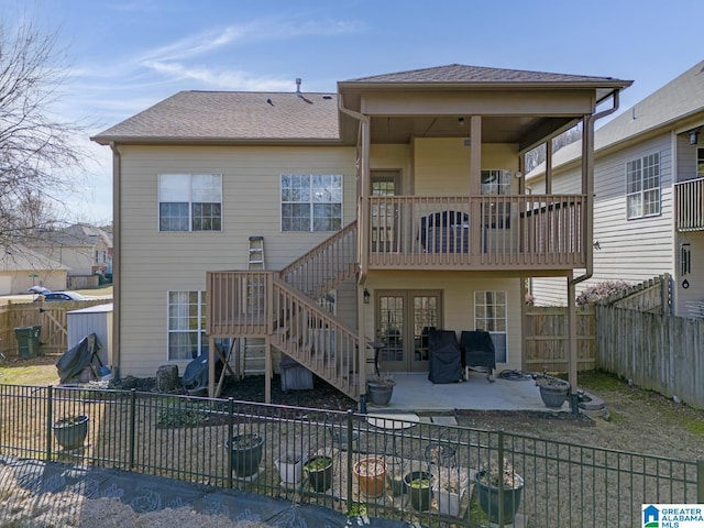 back of house featuring a shingled roof, stairway, a patio area, a balcony, and a fenced backyard