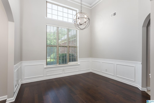 unfurnished dining area with crown molding, an inviting chandelier, and dark wood-type flooring