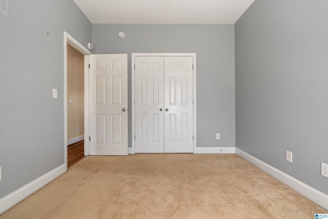 unfurnished bedroom featuring a closet and light colored carpet