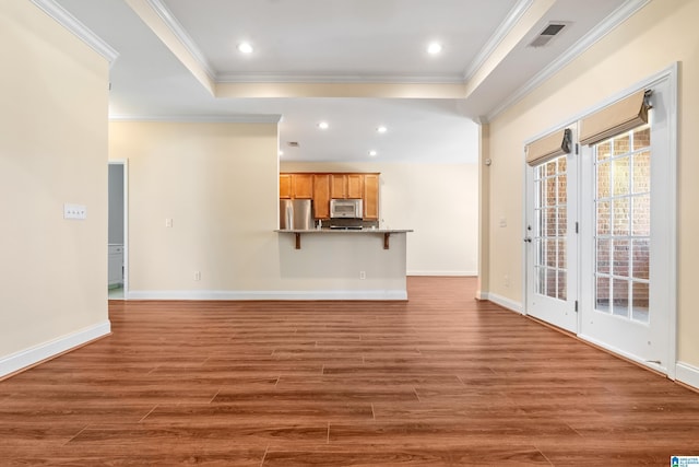 unfurnished living room featuring a tray ceiling, ornamental molding, and dark wood-type flooring