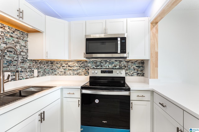 kitchen with white cabinetry, backsplash, sink, and stainless steel appliances