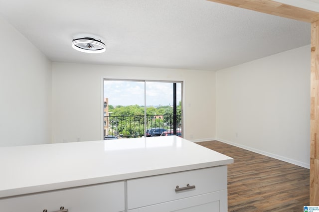 kitchen with a textured ceiling, white cabinets, and dark hardwood / wood-style flooring