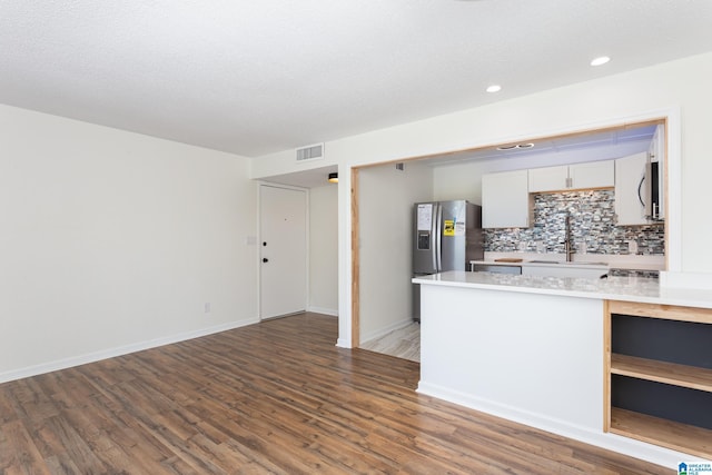 kitchen with sink, a textured ceiling, dark wood-type flooring, white cabinets, and decorative backsplash