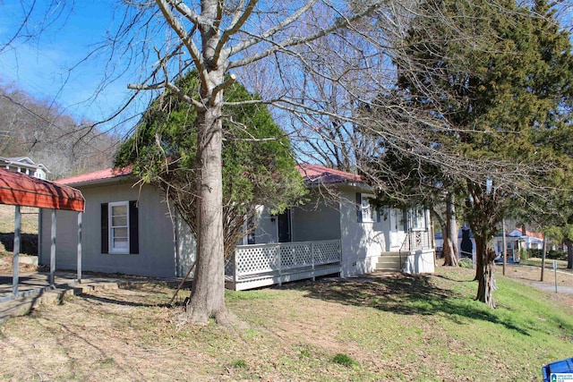 view of front of home with a front yard, covered porch, and metal roof