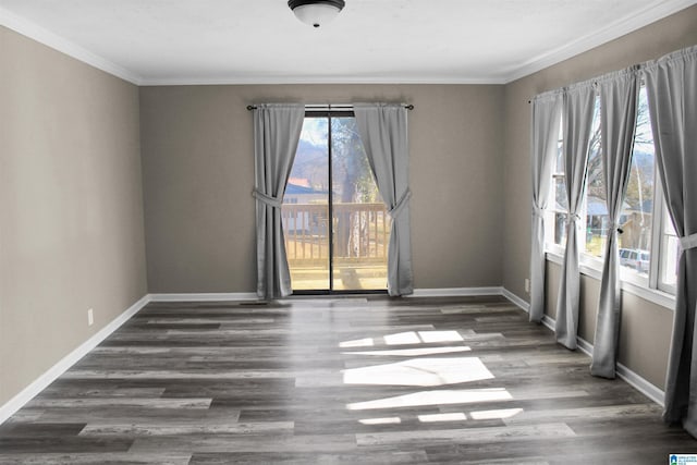 spare room with ornamental molding, baseboards, and wood finished floors