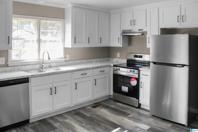 kitchen with under cabinet range hood, wood finished floors, a sink, white cabinets, and appliances with stainless steel finishes