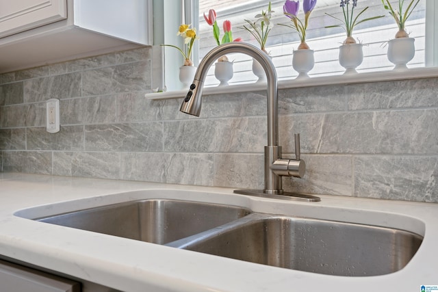 interior details with light countertops, a sink, and white cabinetry