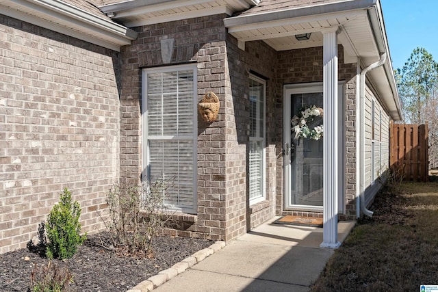 doorway to property with brick siding and fence