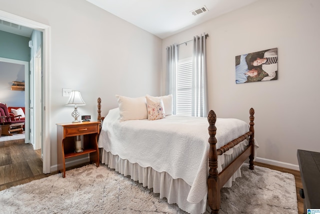 bedroom with wood finished floors, visible vents, and baseboards