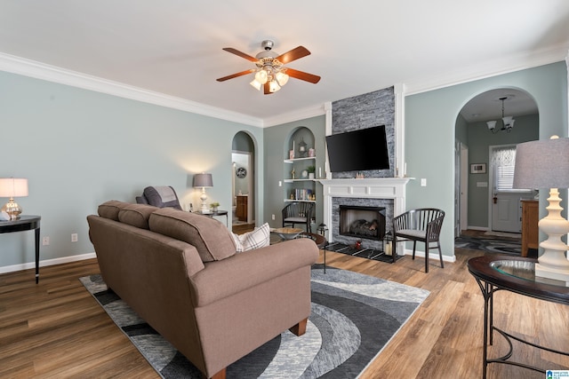 living room featuring crown molding, a fireplace, baseboards, and wood finished floors