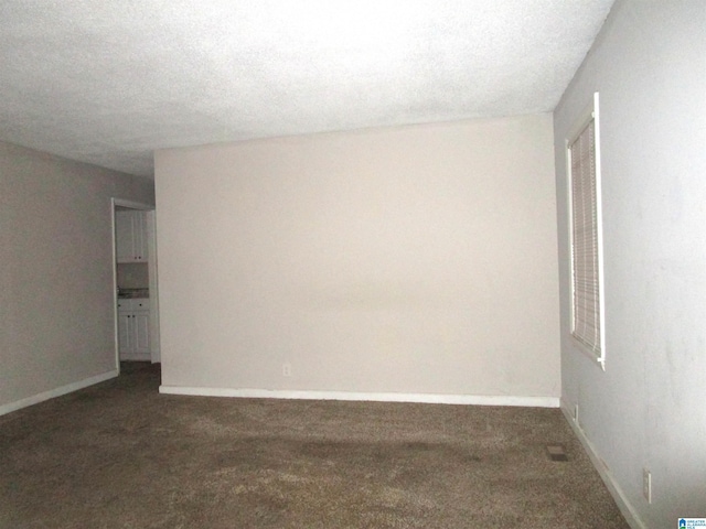 carpeted empty room featuring a textured ceiling