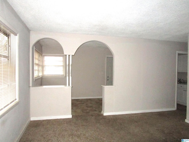 empty room featuring dark carpet and a textured ceiling