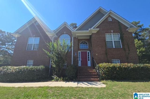 view of front of house featuring entry steps, brick siding, and a front yard