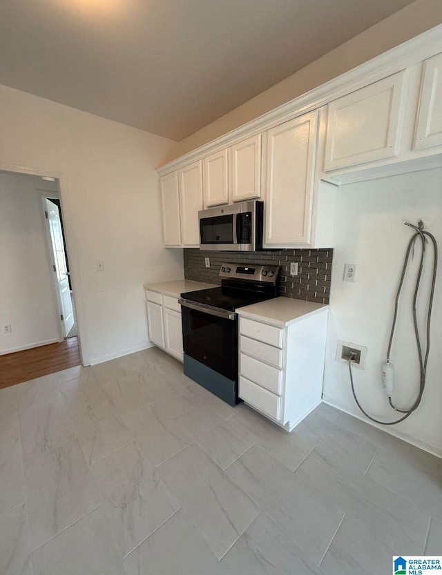 kitchen featuring marble finish floor, stainless steel appliances, light countertops, decorative backsplash, and white cabinetry