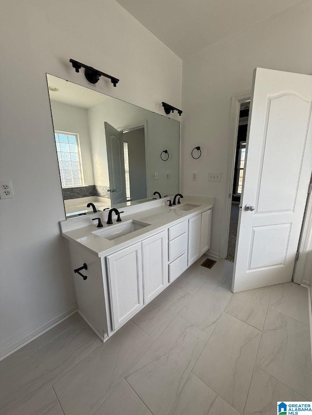 bathroom with marble finish floor, a sink, baseboards, and double vanity