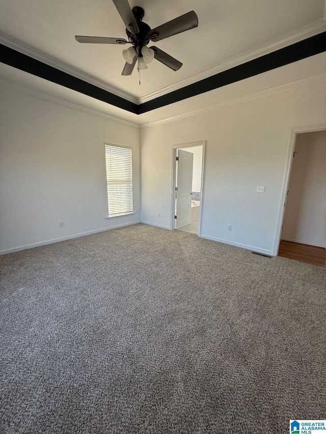 carpeted empty room featuring ornamental molding, a raised ceiling, ceiling fan, and baseboards