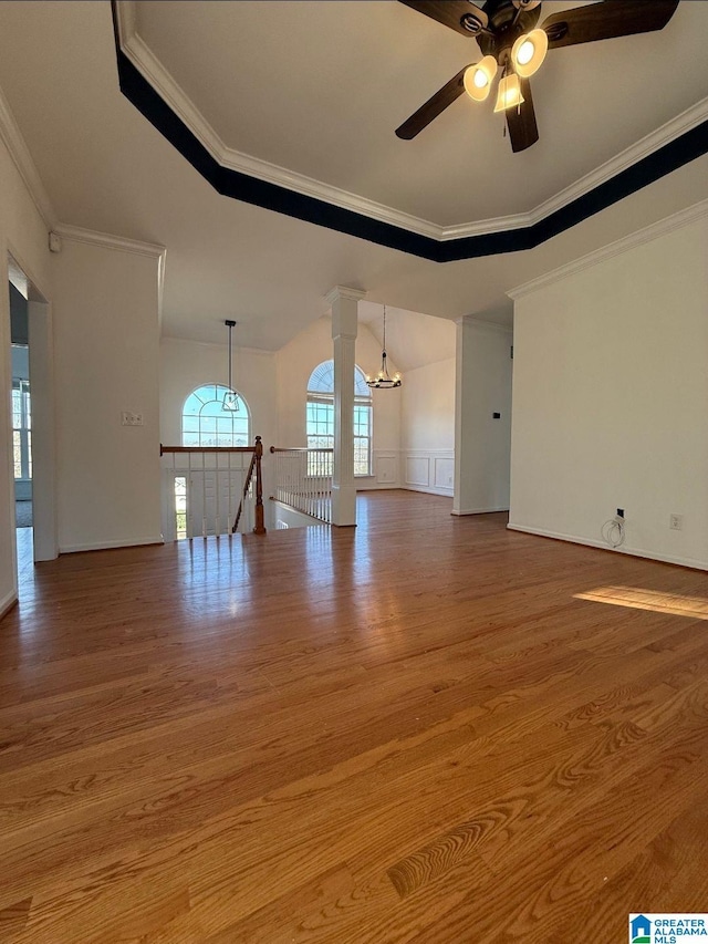 unfurnished living room with a ceiling fan, crown molding, ornate columns, and wood finished floors