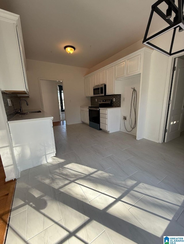 kitchen featuring a sink, white cabinets, electric stove, decorative backsplash, and stainless steel microwave