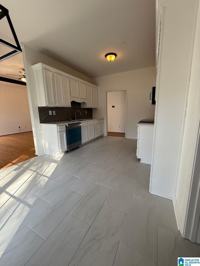 kitchen featuring tasteful backsplash, white cabinets, a ceiling fan, dishwasher, and a sink